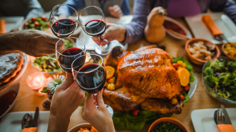 people clinking red wine glasses with turkey