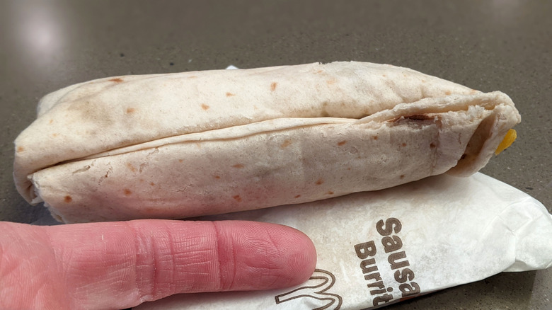 McDonald's sausage burrito with finger for scale