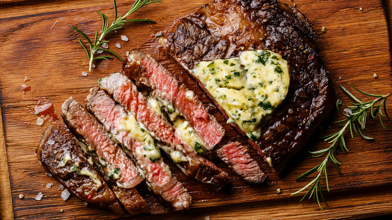 green flecked compound butter on sliced steak