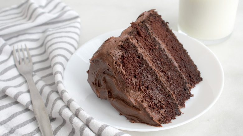 Slice of chocolate cake beside a glass of milk