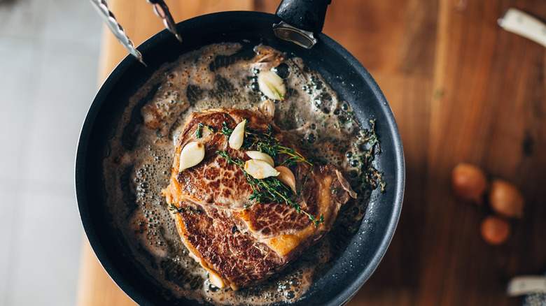 ribeye steak searing in pan