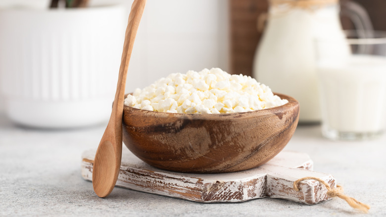 Cottage cheese in wooden bowl with a wooden spoon beside it