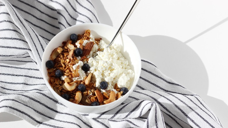 A bowl of cottage cheese, granola, nuts, and blueberries