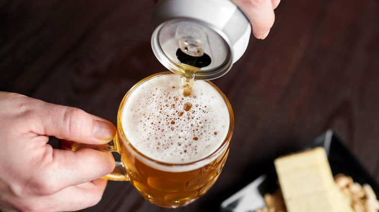 Someone with pouring a beer into a glass