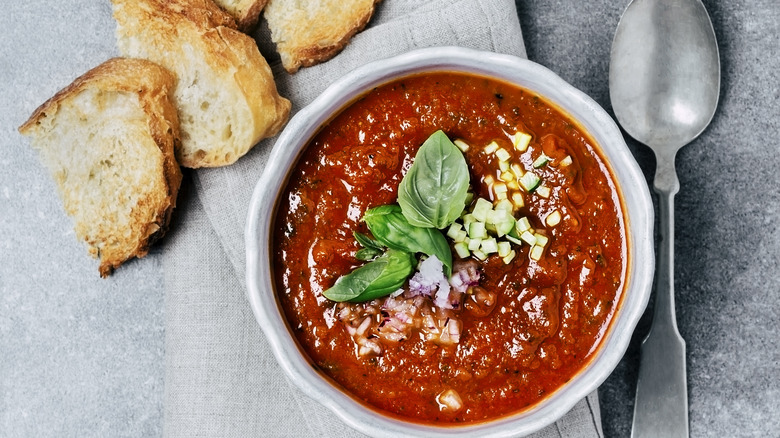 A bowl of soup next to bread.