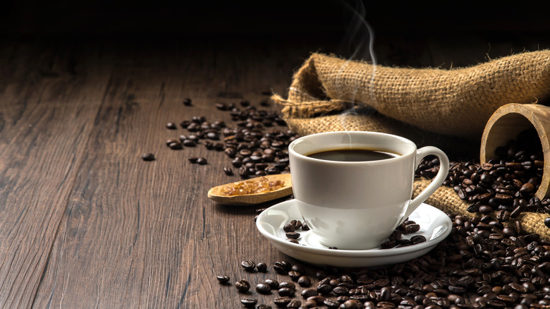 Full coffee cup surrounded by beans