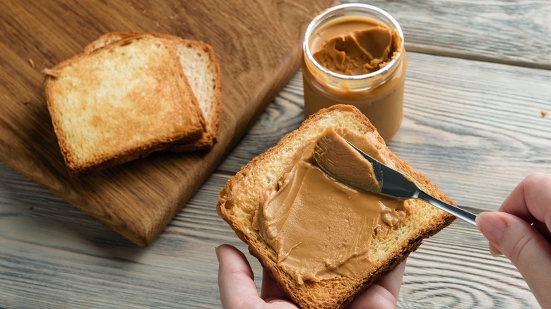 Spreading peanut butter on bread