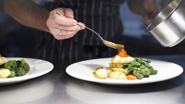 chef plating dish with sauce