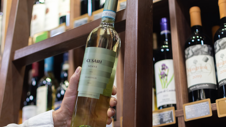 Hand holds Soave bottle in wine shop