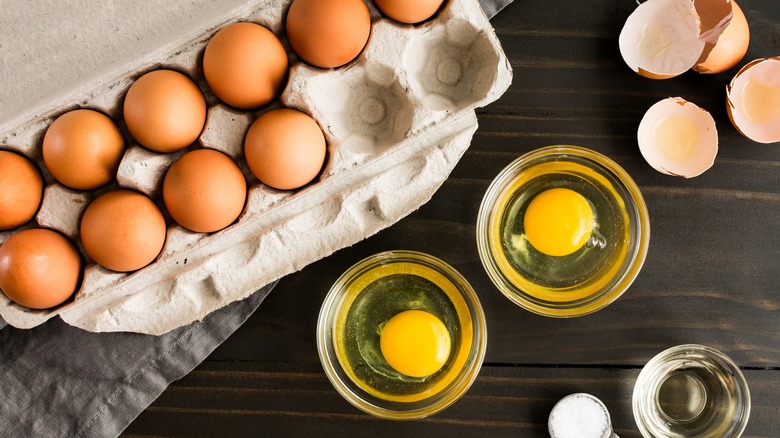 carton of eggs and cracked eggs in two bowls