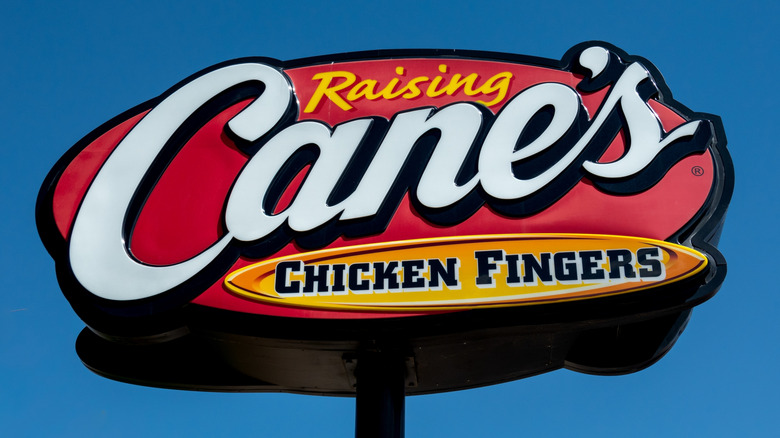 An exterior restaurant sign for Raising Cane's Chicken Fingers.