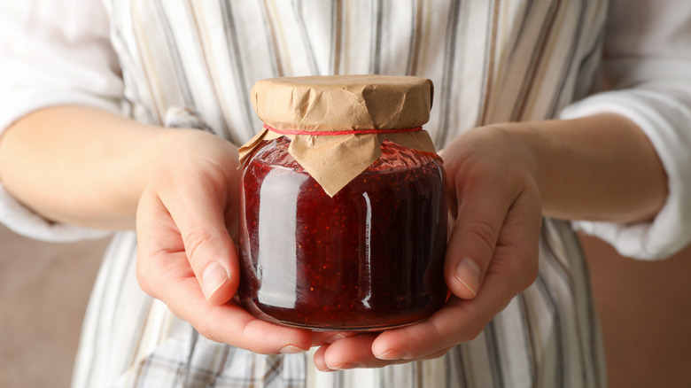 Person in apron holding preserves