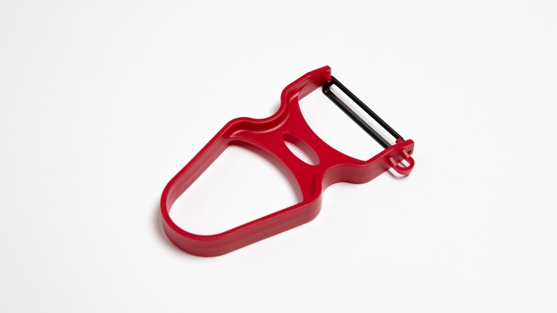 Red vegetable peeler on white background