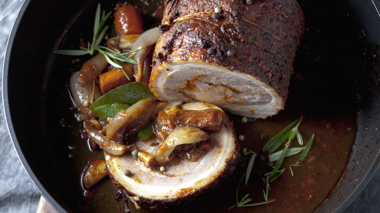 Close up of pork roast with vegetables and herbs