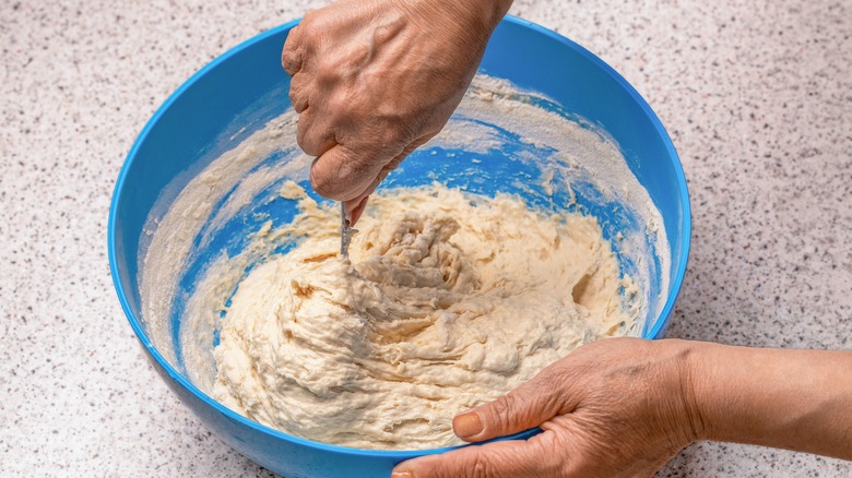 woman stirring dough in blue bowl