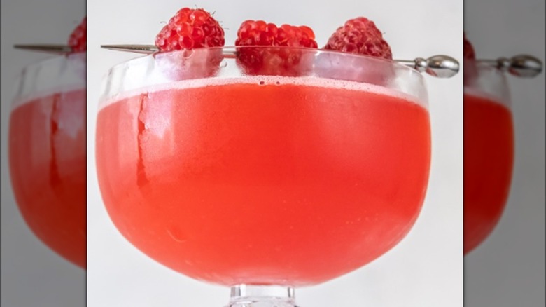 A Blinker cocktail garnished with a trio of raspberries