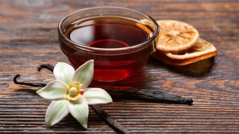 Bowl of vanilla syrup with vanilla pods and flower