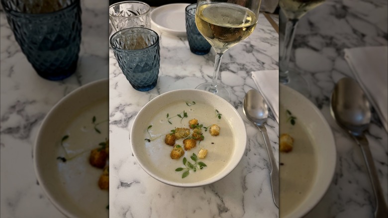 Bowled potato soup with a glass of white wine