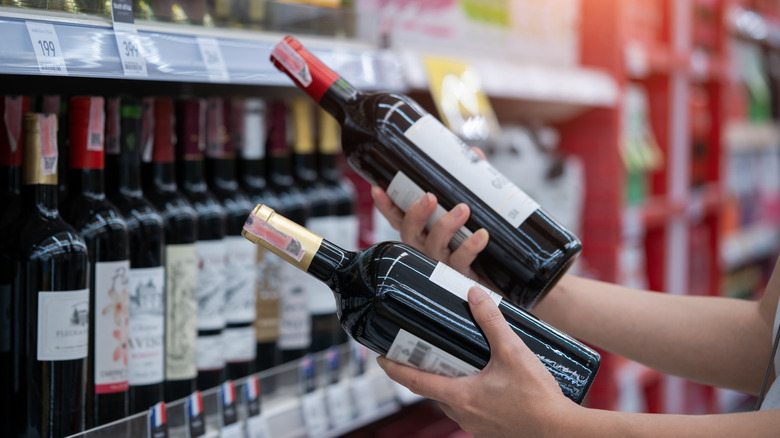 A person analyzing two bottles of wine.