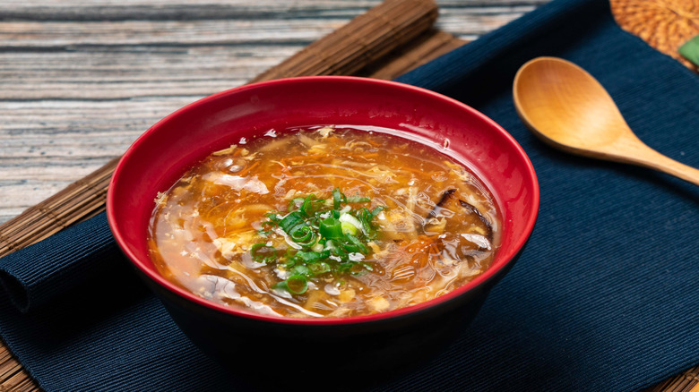 Hot and sour soup in a red bowl with wooden spoon