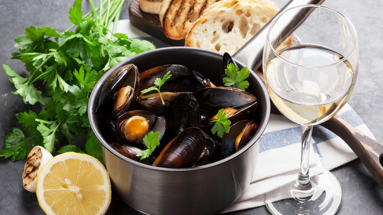 Pot of mussels alongside a glass of white wine