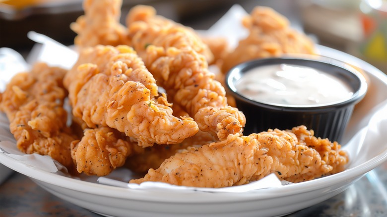 Crispy chicken tenders beside a cup of ranch