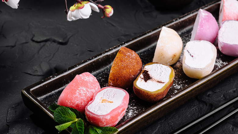 Different flavors of mochi ice cream cut in half and laid out on a black serving dish