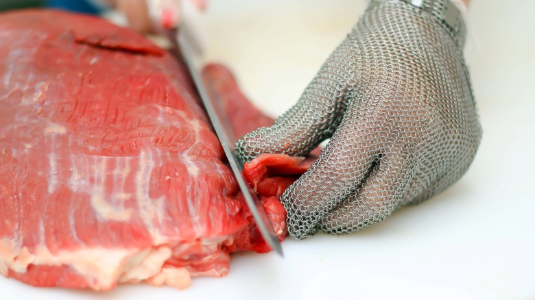 butcher trimming large cut of meat