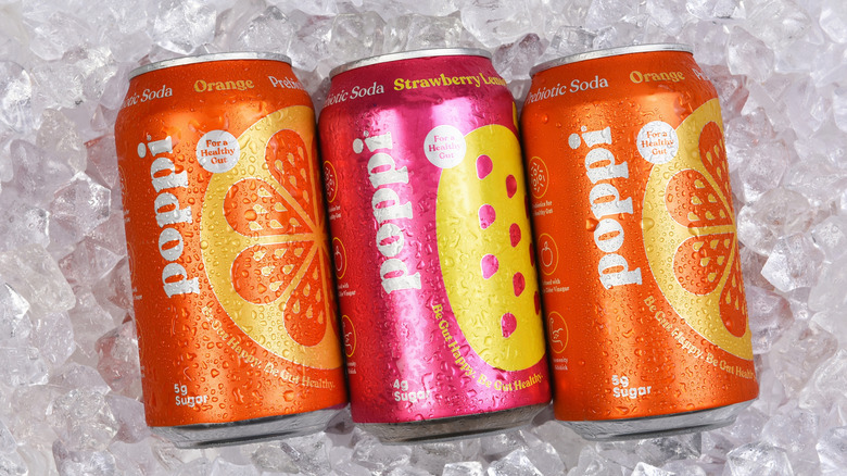 Three cans of Poppi soda on ice