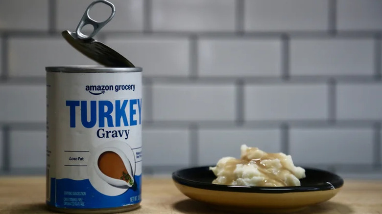 An open can of Amazon Grocery Turkey gravy next to a plate of mashed potatoes and and gravy
