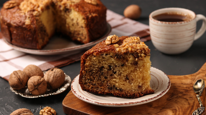 slice of coffee cake on a plate with coffee cup and nutmeg nearby