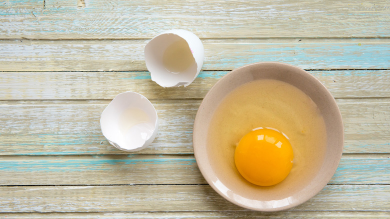 Raw egg and shells on wooden background