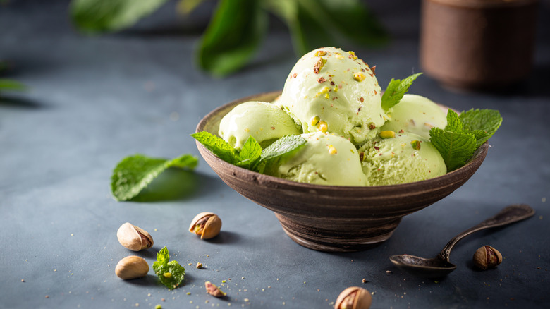 Bowl of pistachio flavored ice cream with nuts throughout