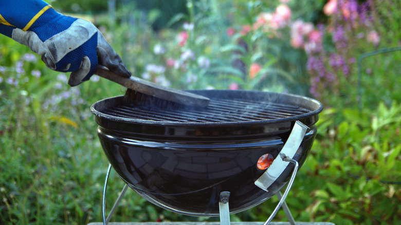 Person cleaning the grates of a grill