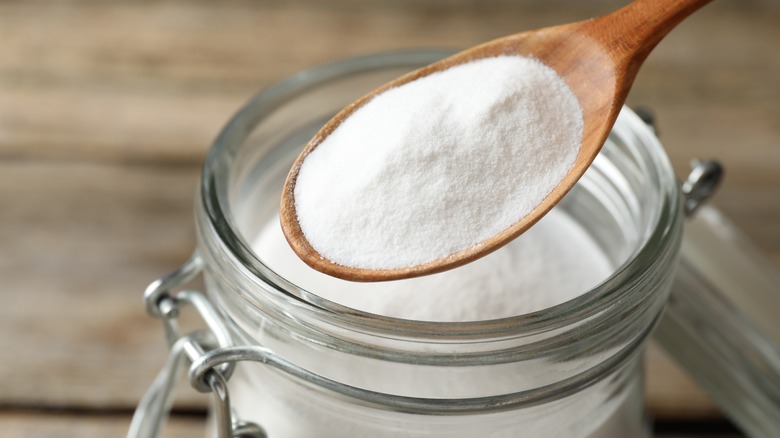 Taking out fine white powder with a wooden spoon from a jar