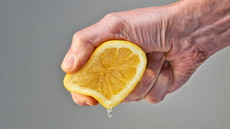 A hand squeezing half of lemon