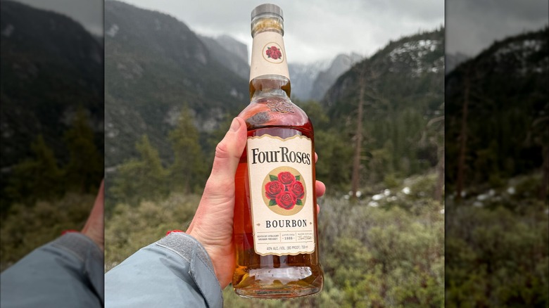 A hand holding a bottle of Four Roses