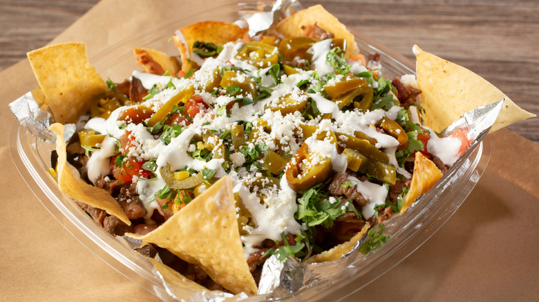 Nachos topped with jalapeños, cilantro, sour cream, and crumbled cotija cheese