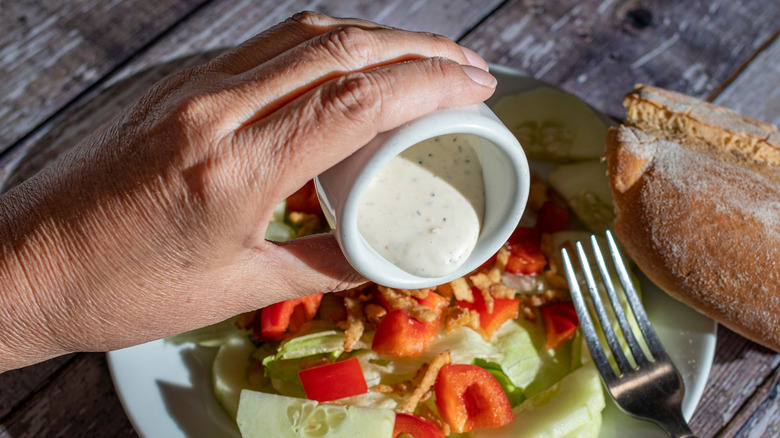 Pouring creamy dressing over salad