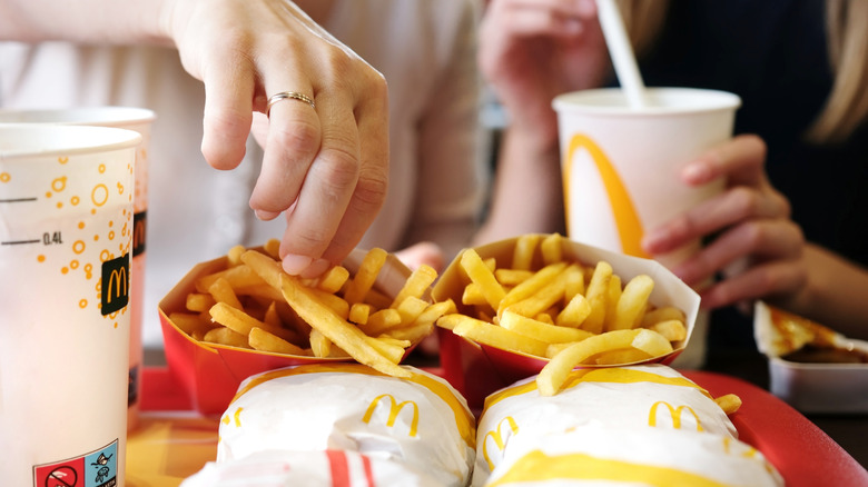 person eating fries off a tray of McDonald's food items