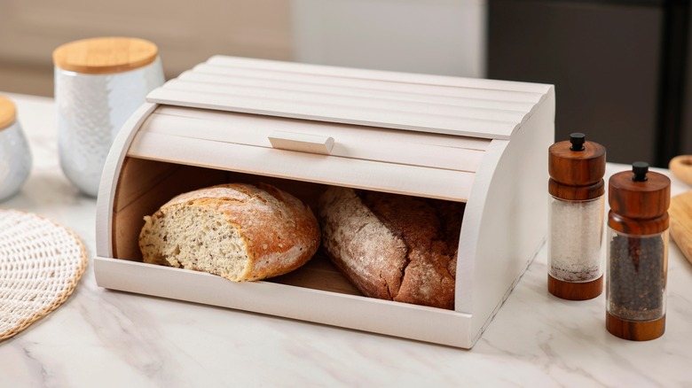 Cut loaf of bread in white bread box