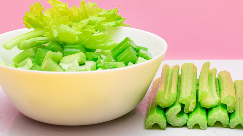 Cut celery on a table and in a white bowl