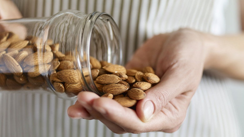 woman pouring glass jar almonds