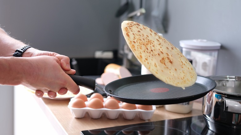 person flipping pancake in pan