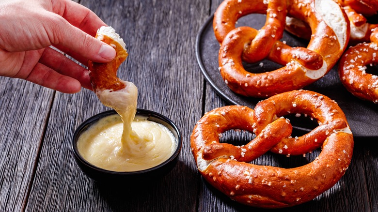 dipping pretzel into cheese dip