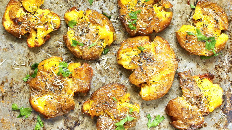 crispy smashed potatoes on a tray topped with parsley and parmesan