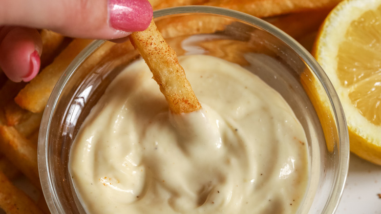 close up of a fry being dipped in aioli