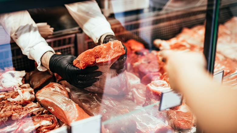 holding steak at butcher counter