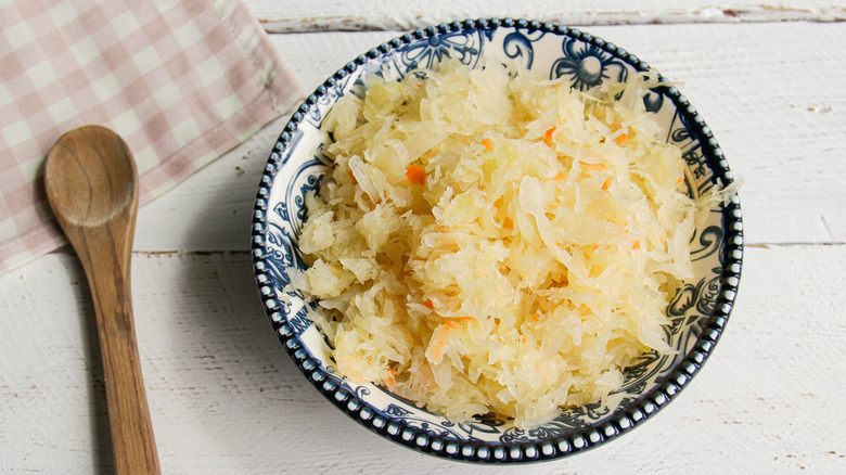 sauerkraut in a blue and white patterned bowl with wooden spoon