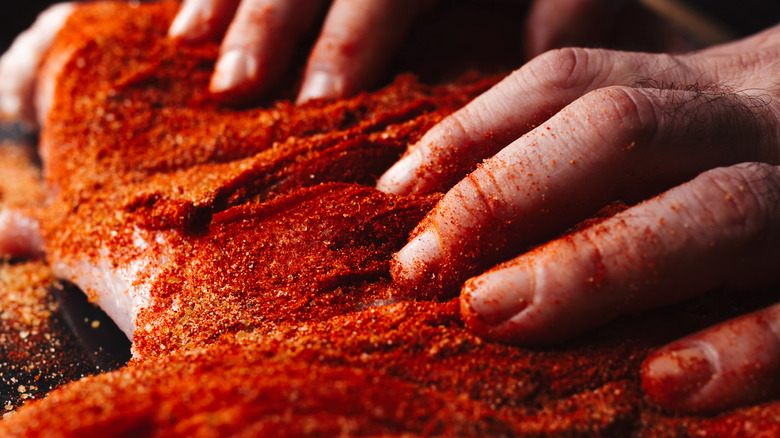 hands grounding rub into meat